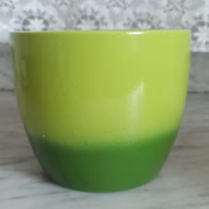 May include: A green ceramic planter with a light green top and a darker green bottom.