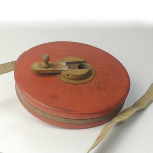 May include: A red and brown tape measure with a wooden handle and a metal hook. The tape measure is labeled "Chesterfield" and has a white and black measuring tape.