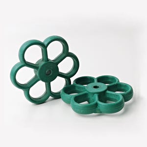 May include: Two green plastic flower-shaped wheels with six points each. The wheels have a hole in the center.