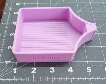 May include: A light purple plastic diamond painting tray with a textured surface and the words "Tall Boy" printed on the bottom.