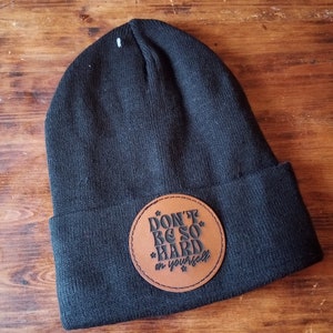 May include: Black beanie with a brown leather patch that says "Don't be so hard on yourself".