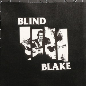 May include: Black and white patch with the text "BLIND BLAKE" and a silhouette of a man playing a guitar.