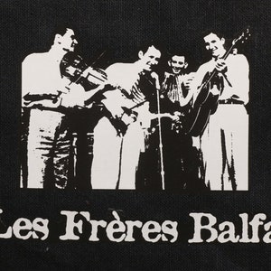 May include: Black and white image of a band called "Les Frères Balfa" with four musicians playing instruments. The band members are standing in a row, and the image is cropped at the shoulders.