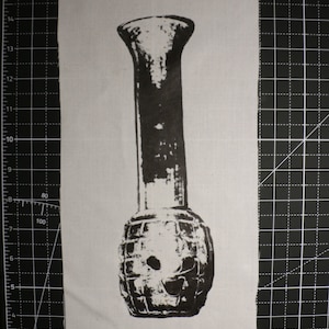 May include: Black and white image of a vase shaped like a grenade. The vase has a narrow neck and a wide, round base.
