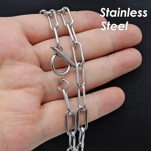 Könnte beinhalten: Eine silberne Kettenkette mit einem Schiebeverschluss. Die Kette ist aus Edelstahl.