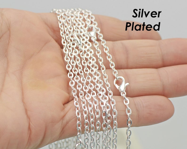 May include: A close-up of a silver plated chain necklace. The chain is made of small, linked circles. The chain is lying on a hand, and the text "Silver Plated" is visible in the upper right corner of the image.