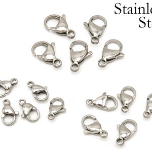 May include: A close-up of 14 silver-toned lobster clasps, made of stainless steel. These clasps are commonly used for jewelry making and crafting.