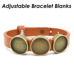 Pode incluir: Uma pulseira ajustável com três configurações de moldura em latão antigo. A pulseira é feita de couro marrom. O texto "Adjustable Bracelet Blanks" está na parte superior da imagem.