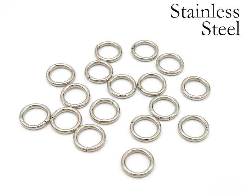 May include: A collection of 15 silver jump rings, made of stainless steel. The rings are all the same size and are arranged in a random pattern on a white background.