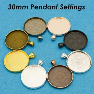 May include: Assortment of eight 30mm round pendant settings in various finishes, including silver, gold, black, and copper. Each setting has a loop for attaching a chain or cord.