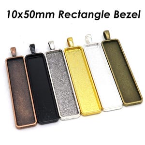 May include: Six different coloured metal rectangle bezels, each with a loop at the top for hanging. The bezels are 10mm by 50mm and are made of silver, gold, black, copper, and two shades of grey.