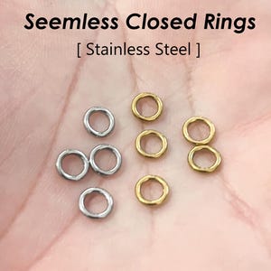 Puede incluir: Primer plano de una mano sosteniendo una variedad de anillos cerrados sin costuras en oro y plata. Los anillos son de acero inoxidable. Anillos cerrados sin costuras [Acero inoxidable]