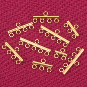 May include: Gold-toned metal connector pieces for jewelry making. Each piece has multiple loops for attaching chains or cords.