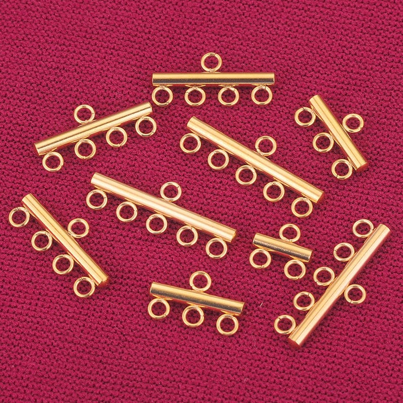 May include: Gold-toned metal connector pieces for jewelry making. Each piece has multiple loops for attaching chains or cords.