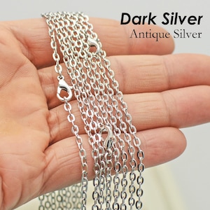 May include: Multiple strands of silver chain, shown in a hand, with the text "Dark Silver Antique Silver" above the chain.