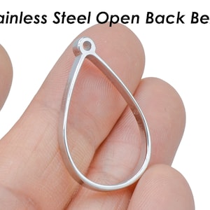 Puede incluir: Una montura abierta de plata en forma de lágrima para la elaboración de joyas.