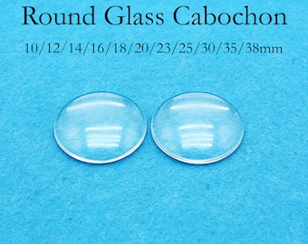 May include: Two clear glass cabochons on a blue background. The cabochons are round and have a smooth, polished surface. The text "Round Glass Cabochon" and "10/12/14/16/18/20/23/25/30/35/38mm" is printed above the cabochons.