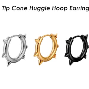 May include: Three huggie hoop earrings in silver, gold, and black, each with a cone-shaped tip on every point. The earrings have a punk rock aesthetic.
