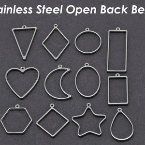 May include: A set of 12 stainless steel open back bezels in various shapes, including a heart, a crescent moon, a star, a teardrop, a circle, a square, a rectangle, a hexagon, and a diamond. The bezels are all silver in colour and have a smooth, polished finish.