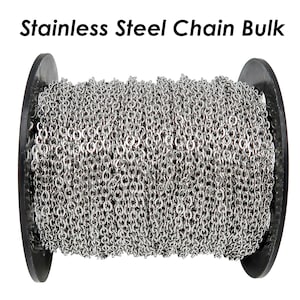 May include: A spool of silver stainless steel chain. The chain is wound tightly around the spool, which is black and has a smooth surface.
