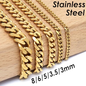 Op de afbeelding: Goudkleurige roestvrijstalen gourmetkettingen in verschillende breedtes: 8 mm, 6 mm, 5 mm, 3,5 mm en 3 mm. De kettingen worden gepresenteerd op een houten oppervlak met de tekst "Stainless Steel".
