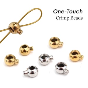 May include: Gold and silver-toned One-Touch Crimp Beads, spherical in shape with a small protruding side tab. One gold bead is threaded onto a thin gold wire loop. The text One-Touch Crimp Beads is displayed in the upper right corner.
