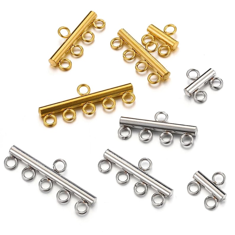 May include: A set of gold and silver metal connector pieces for jewelry making. The pieces have a cylindrical shape with multiple loops on each end.