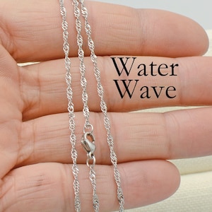 May include: Three silver chains with a water wave design. The chains are on a hand and the text "Water Wave" is written on the hand.