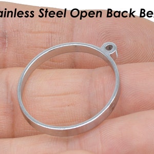 Peut inclure: Une bélière ouverte en acier inoxydable argenté pour la fabrication de bijoux. La bélière est ronde et possède un petit trou en haut.