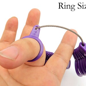 May include: Purple plastic ring sizer with a metal chain. The sizer is numbered from 6 to 13.