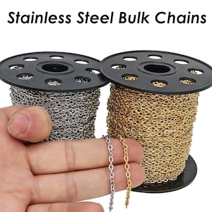 May include: Two spools of stainless steel chain, one gold and one silver, on black spools. The chain is on a white background.