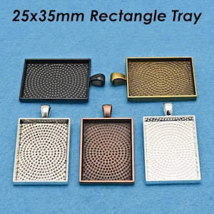 May include: Four different metal trays, each measuring 25x35mm. The trays are silver, black, copper, and gold. Each tray has a textured surface and a loop for hanging.