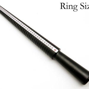 May include: Black plastic ring sizer with white markings for measuring ring sizes. The sizer is marked with sizes from 3 to 13.