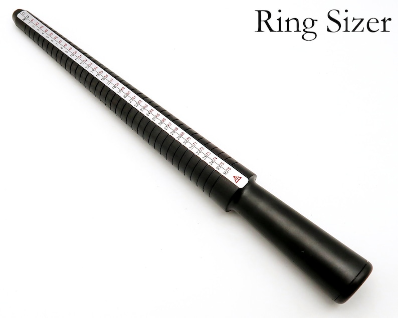 May include: Black plastic ring sizer with white markings for measuring ring sizes. The sizer is marked with sizes from 3 to 13.