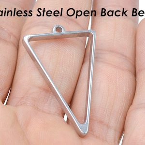 May include: A silver triangle-shaped open back bezel pendant with a loop at the top.