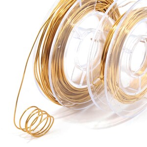May include: A spool of gold-colored wire on a clear plastic spool. The wire is wound tightly around the spool and is ready to be used for crafting projects.