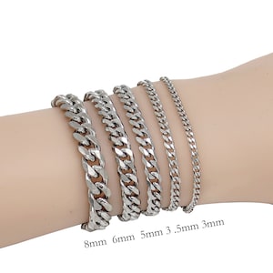 Op de afbeelding: Een collectie zilverkleurige gourmetarmbanden in verschillende breedtes: 8mm, 6mm, 5mm, 3,5mm en 3mm. De armbanden worden getoond op een licht getinte arm. De afbeelding is goed belicht en toont de reflectie van het metaal.