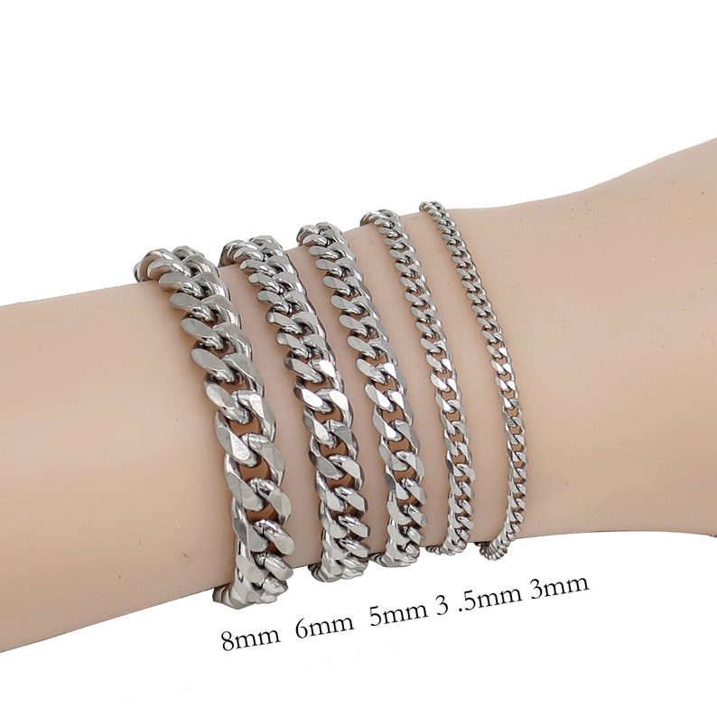 Op de afbeelding: Een collectie zilverkleurige gourmetarmbanden in verschillende breedtes: 8mm, 6mm, 5mm, 3,5mm en 3mm. De armbanden worden getoond op een licht getinte arm. De afbeelding is goed belicht en toont de reflectie van het metaal.