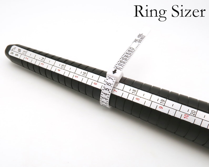 May include: A black ring sizer with white markings for measuring ring sizes from 1 to 20. The sizer has a white tape measure with markings for sizes 10 to 19.