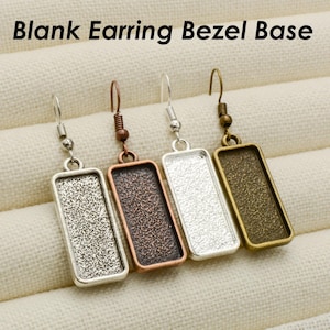 May include: Four blank earring bezel bases in different finishes: silver, copper, white, and gold. The bases are rectangular and have a textured surface. Blank Earring Bezel Base.