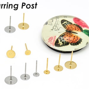 Puede incluir: Surtido de postes de pendientes en oro y plata. Los postes son de diferentes tamaños y tienen respaldos redondos planos. Los postes de pendientes se muestran sobre una superficie blanca.