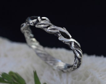 May include: A silver ring with a twisted band and a design of intertwining branches. The ring is on a white background.