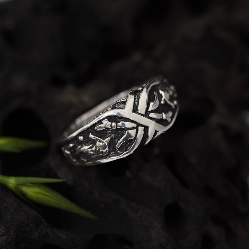 May include: A silver ring with a detailed, intricate design of interwoven branches and leaves.