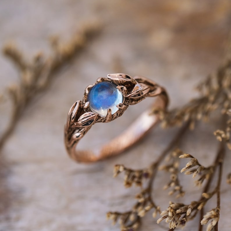 Puede incluir: Un anillo de oro rosa con un delicado dise&ntilde;o de hojas y una piedra de luna redonda.