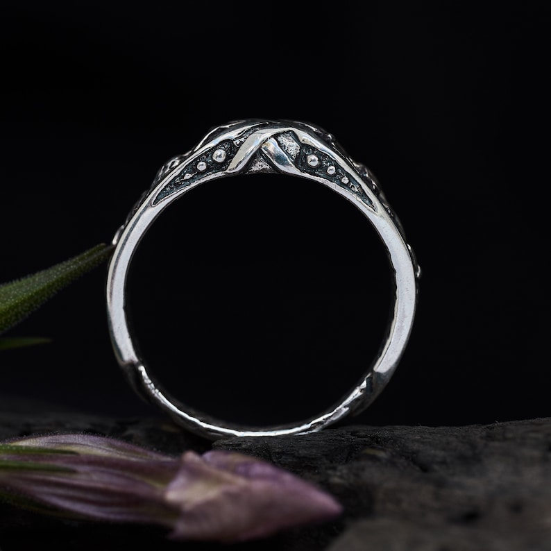 May include: A silver ring with a textured, twisted band and small dots along the edges.