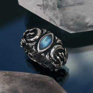 Può includere: Un anello d'argento con una pietra di luna blu incastonata in un design dettagliato e ornato.