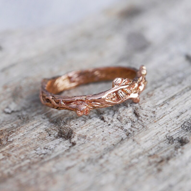 Pu&ograve; includere: Un anello in oro rosa con un design a forma di ramo. L'anello &egrave; realizzato per assomigliare a un ramo con foglie.