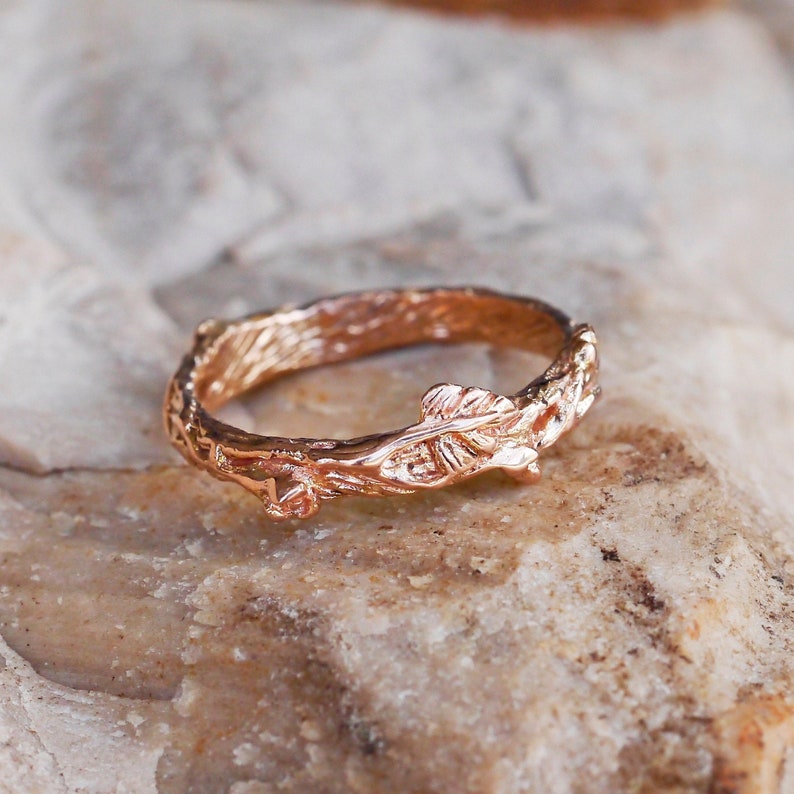 Pu&ograve; includere: Un anello in oro rosa con un design a ramo con una foglia. L'anello &egrave; in metallo e ha una finitura liscia.