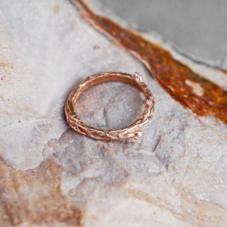 Pu&ograve; includere: Un anello in oro rosa con un design unico a forma di ramo. L'anello &egrave; in metallo e ha una finitura liscia e lucida.