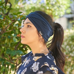 Mexican female model wearing a ponytail and Autumn navy viscose criss cross headband for women with a blue floral dress in Fall